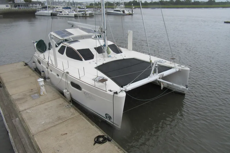 Slide: The Image of 2001 Catana 471 catamaran docked at a marina, featuring solar panels and sleek design. - 156