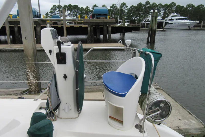 Slide: The Image of Helm station of 2001 Catana 471 catamaran docked at marina with lush trees. - 55