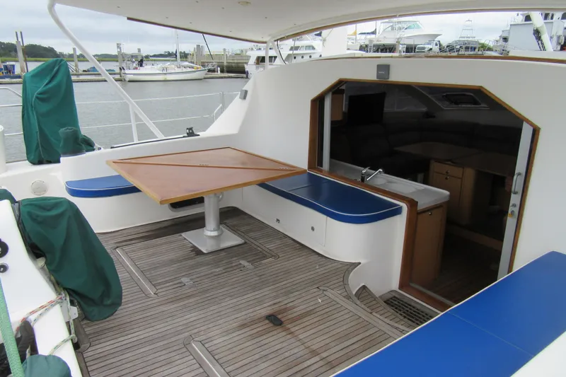 Slide: The Image of 2001 Catana 471 yacht cockpit with wooden table and seating, docked at marina. - 6