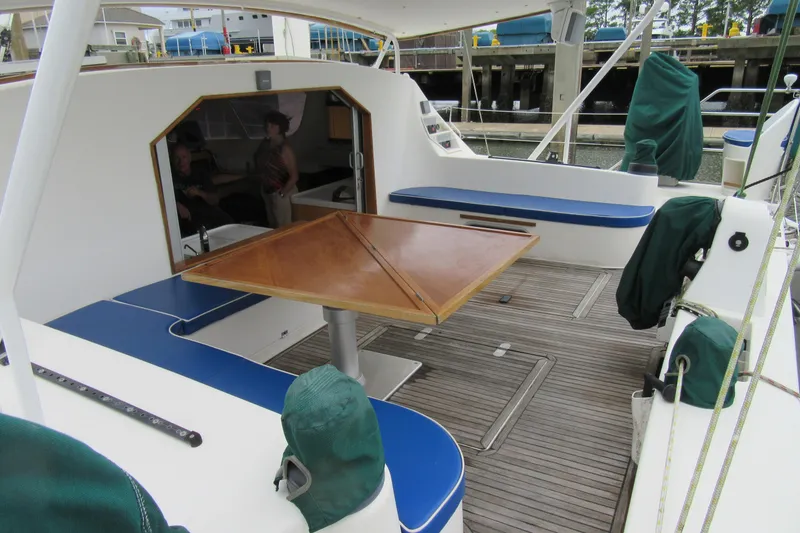Slide: The Image of 2001 Catana 471 yacht cockpit with wooden table, blue seating, and covered equipment. - 8