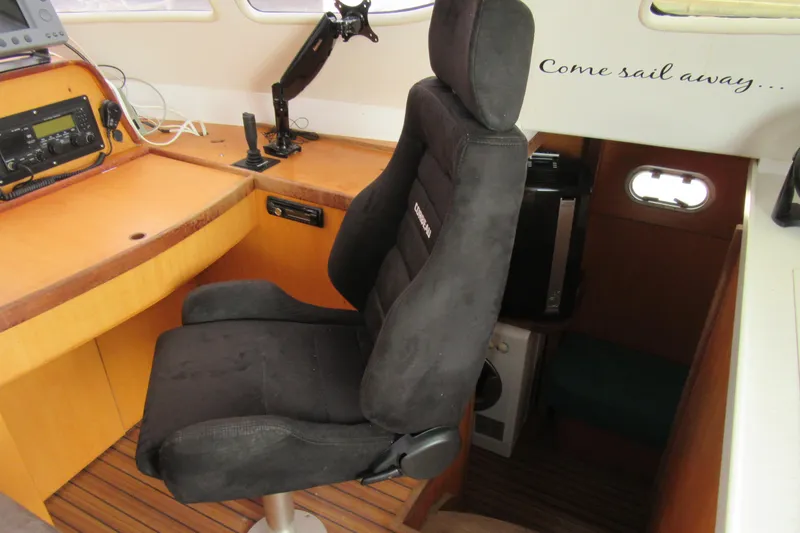 Slide: The Image of Navigation station of 2001 Catana 471 yacht with black captain's chair and wooden interior. - 95