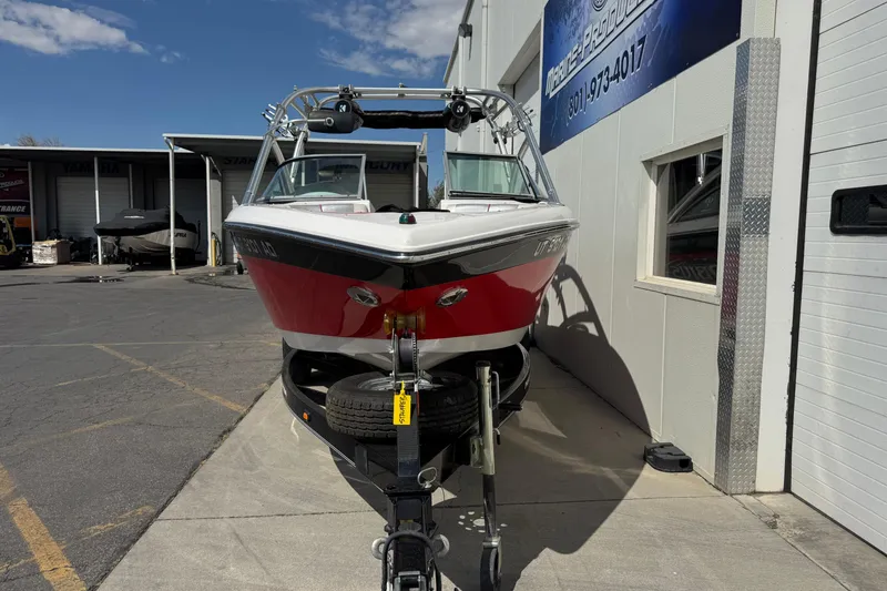 Slide: The Image of 2006 Moomba Mobius XLV boat on trailer, parked outside a building under a clear sky. - 4