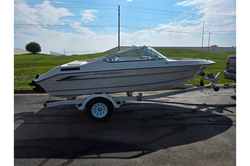 Slide: The Image of 1998 Regal Valanti 176 boat on trailer, parked outdoors under a partly cloudy sky. - 4