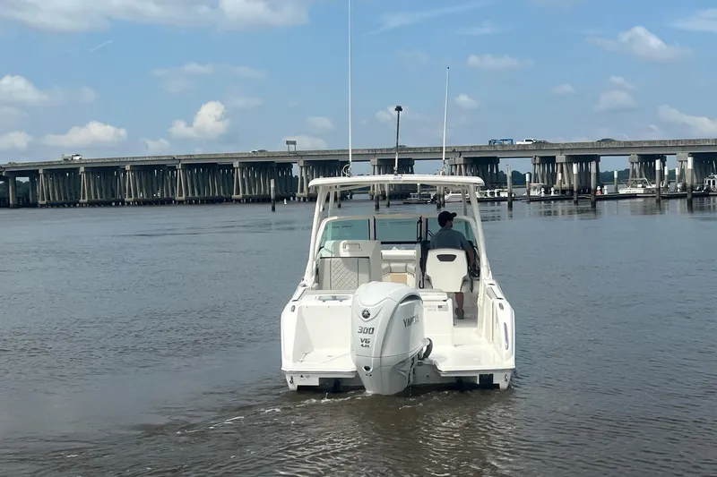 Slide: The Image of 2023 Pursuit DC 246 Dual Console boat on water near a bridge under a blue sky. - 10