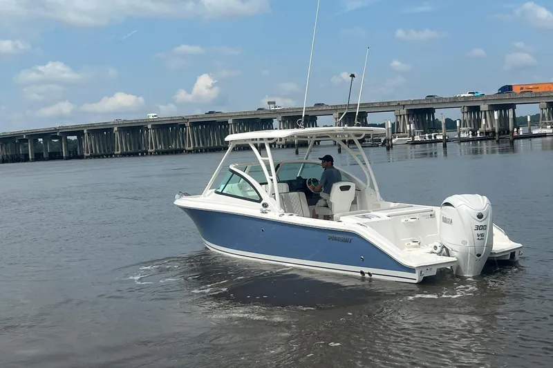 Slide: The Image of 2023 Pursuit DC 246 Dual Console boat on water near a bridge, clear sky. - 12