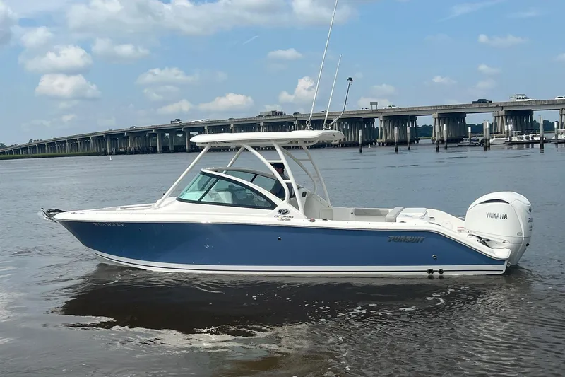 Slide: The Image of 2023 Pursuit DC 246 Dual Console boat on calm water, bridge in background. - 13