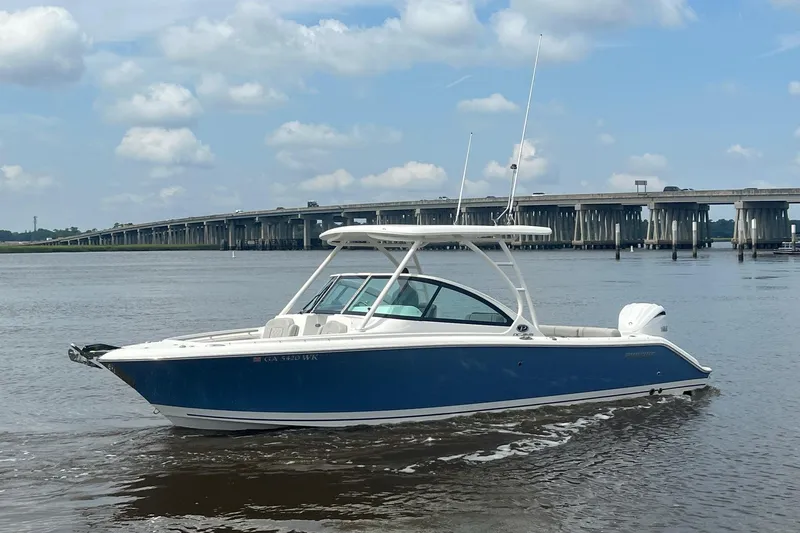 Slide: The Image of 2023 Pursuit DC 246 Dual Console boat on water near a bridge under a cloudy sky. - 15