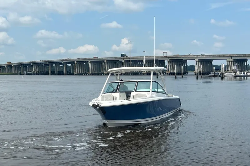 Slide: The Image of 2023 Pursuit DC 246 Dual Console boat cruising near a bridge on a sunny day. - 16