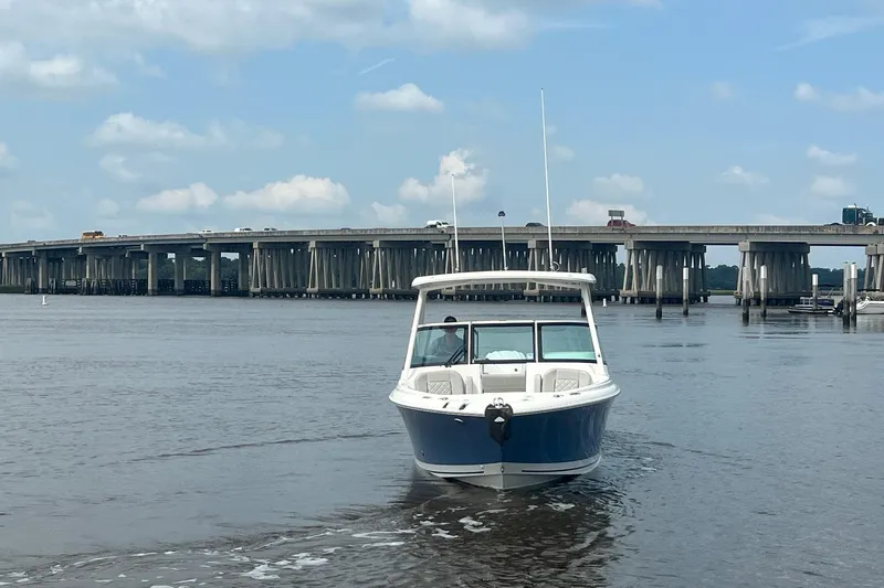 Slide: The Image of 2023 Pursuit DC 246 Dual Console boat on water near a bridge under a blue sky. - 17