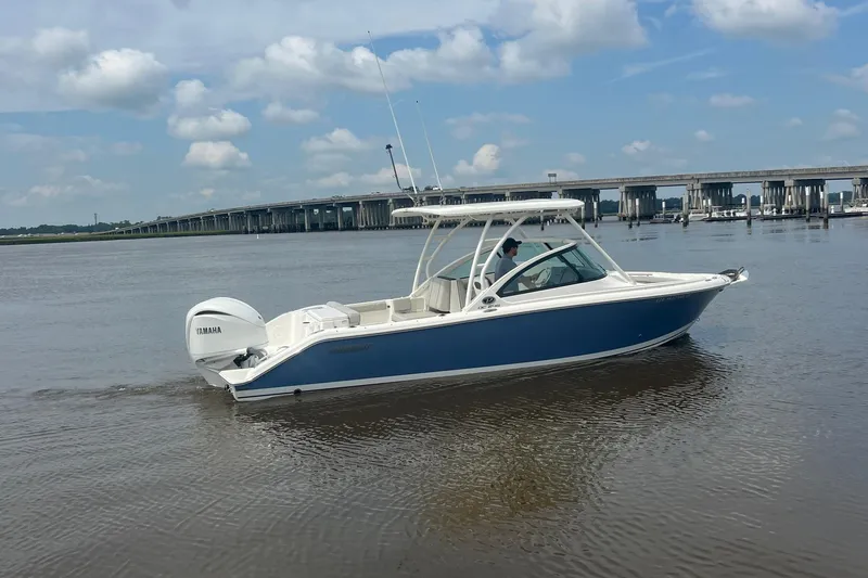 Slide: The Image of 2023 Pursuit DC 246 Dual Console boat on calm water near a bridge. - 8