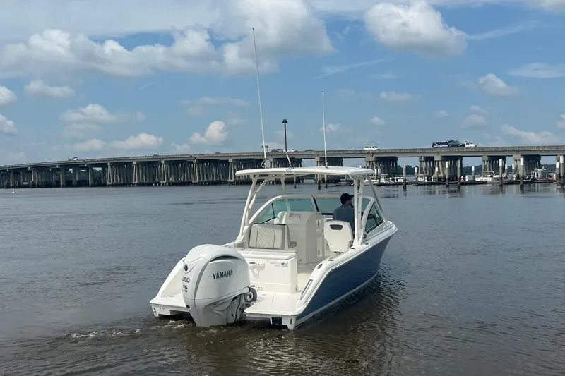 Slide: The Image of 2023 Pursuit DC 246 Dual Console boat on water near a bridge under a cloudy sky. - 9