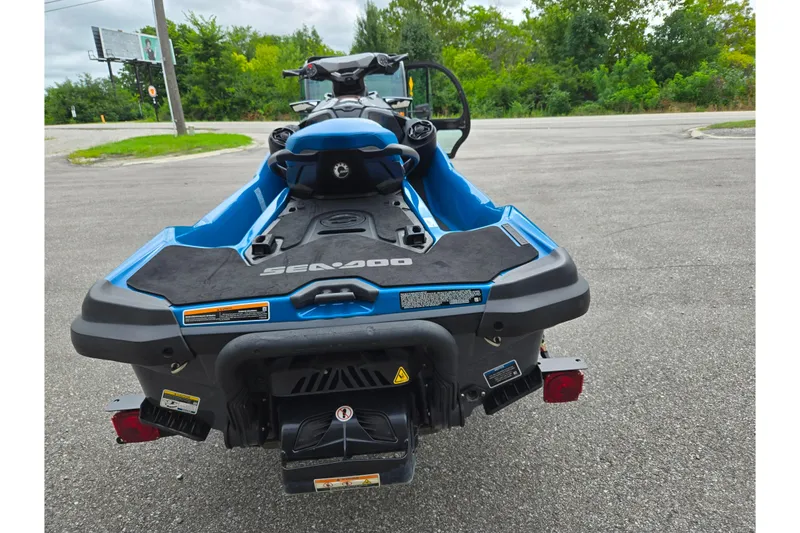 Slide: The Image of 2019 Sea-Doo GTX 230 jet ski, blue, parked on asphalt with greenery background. - 2