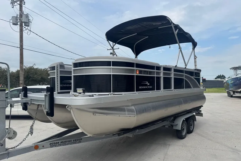 Slide: The Image of 2021 Bennington SX21 pontoon boat on a trailer, parked outdoors under a cloudy sky. - 15