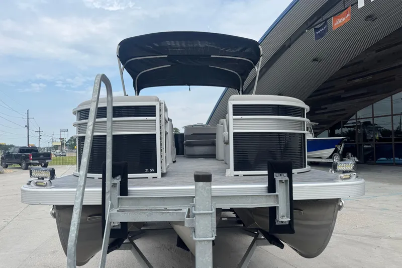 Slide: The Image of 2021 Bennington SX21 pontoon boat on trailer, parked outside a dealership. - 3