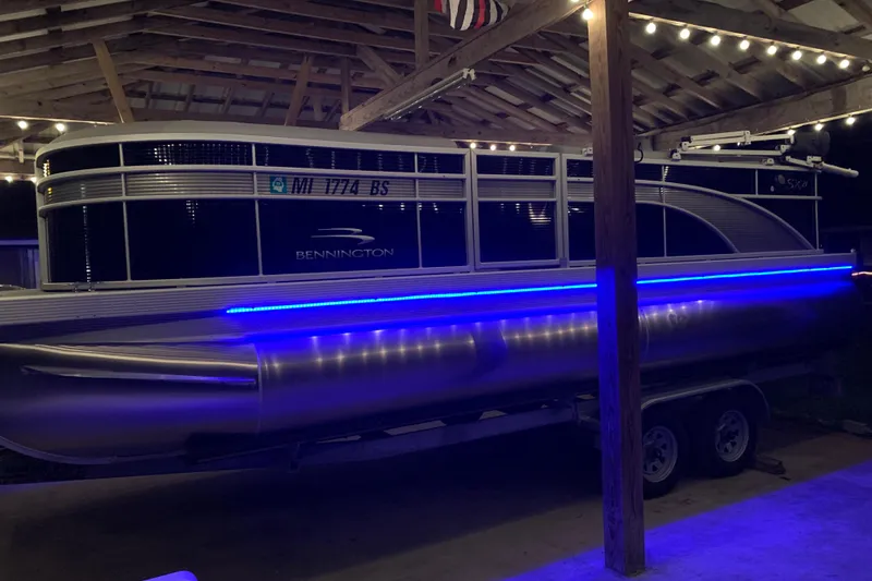 Slide: The Image of 2021 Bennington SX21 pontoon boat with blue LED lights under a wooden shelter. - 4