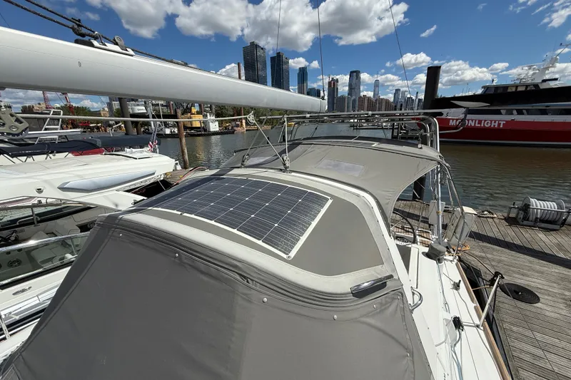 Slide: The Image of Beneteau Oceanis 41 sailboat with solar panel, docked in a marina, city skyline background. - 25
