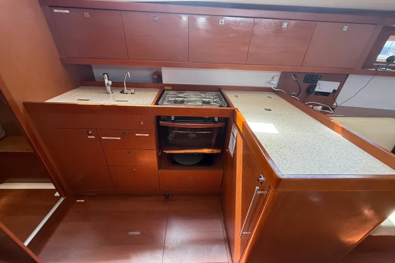 Slide: The Image of 2013 Beneteau Oceanis 41 yacht kitchen with wooden cabinets and modern appliances. - 57
