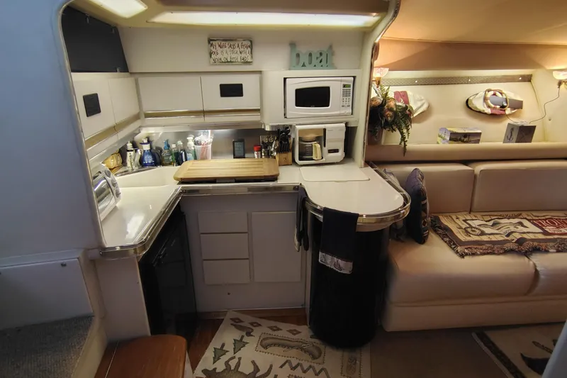 Slide: The Image of 1989 Wellcraft Gran Sport 3400 interior with kitchenette, microwave, and cozy seating area. - 28