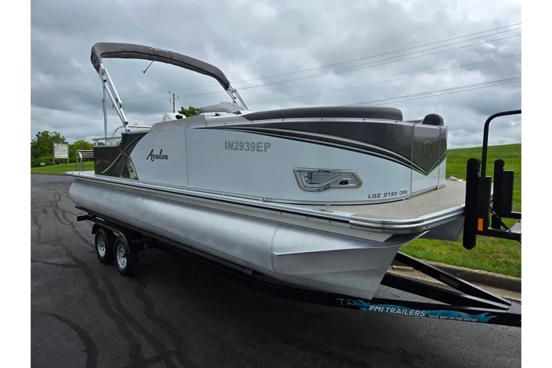 Slide: The Image of 2024 Avalon LSZ Cruise Bench pontoon boat on trailer, parked on a cloudy day. - 5