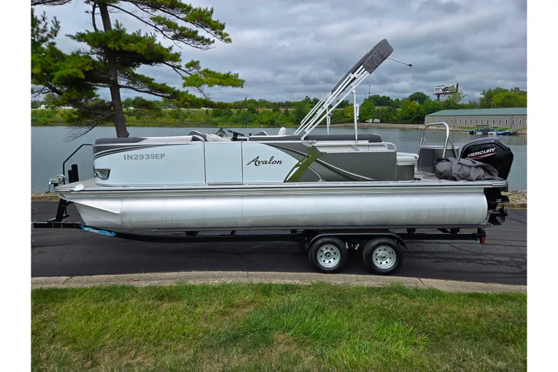 Slide: The Image of 2024 Avalon LSZ Cruise Bench pontoon boat on trailer by a lake. - 9