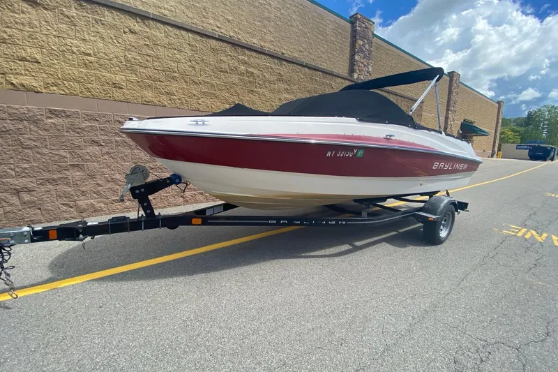 The Image of 2013 Bayliner 185 Bowrider on trailer, parked outdoors, under a partly cloudy sky. - 0
