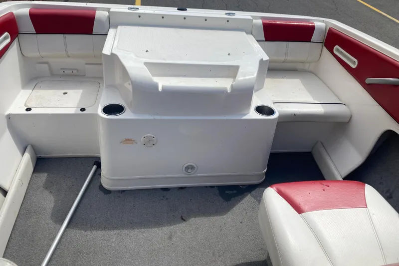 Slide: The Image of 2013 Bayliner 185 Bowrider interior with red and white seating, cup holders, and storage compartments. - 5