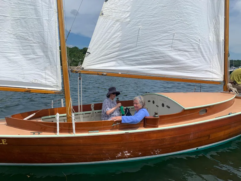 Slide: The Image of 1972 Herreshoff Rozinante sailboat with two people onboard, sailing on a calm lake. - 18