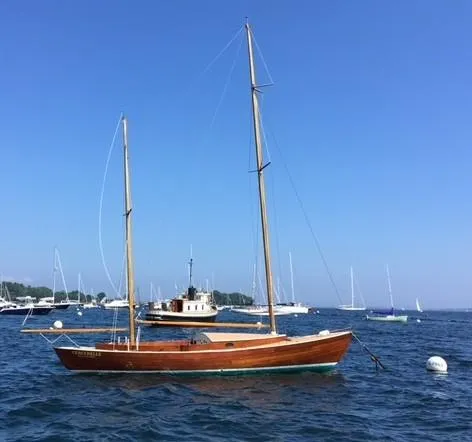 Slide: The Image of 1972 Herreshoff Rozinante sailboat on calm blue water, clear sky background. - 2