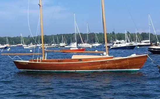 Slide: The Image of 1972 Herreshoff Rozinante sailboat on calm water, surrounded by other boats. - 3