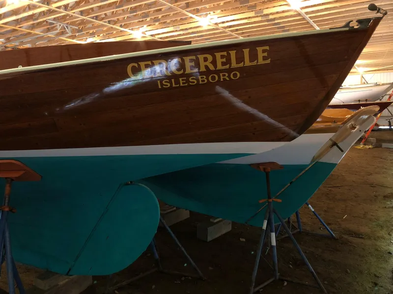 Slide: The Image of 1972 Herreshoff Rozinante sailboat "Cercerelle" in storage, featuring a wooden hull and teal bottom. - 5