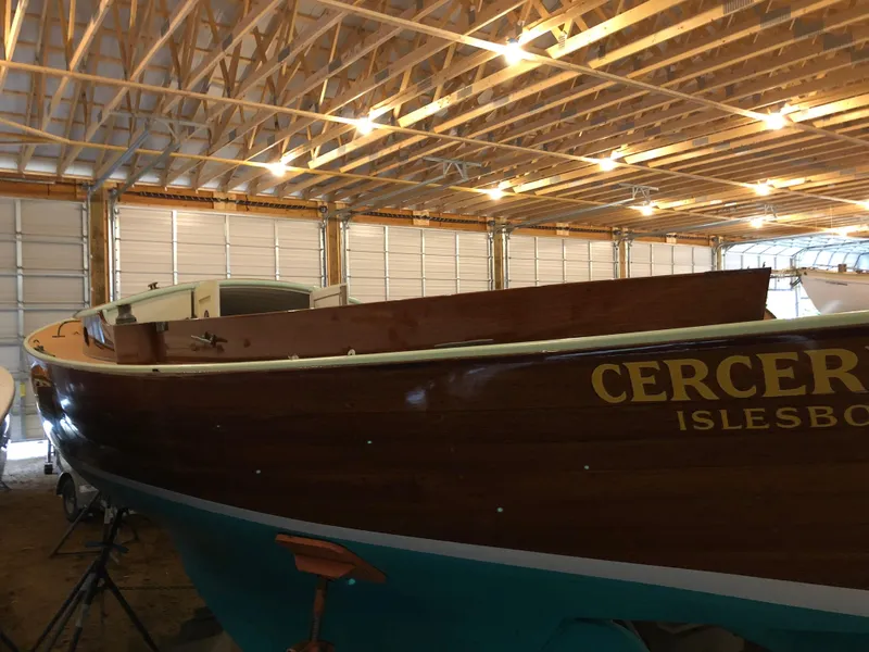 Slide: The Image of 1972 Herreshoff Rozinante sailboat in storage, wooden hull, partial view, indoor lighting. - 6