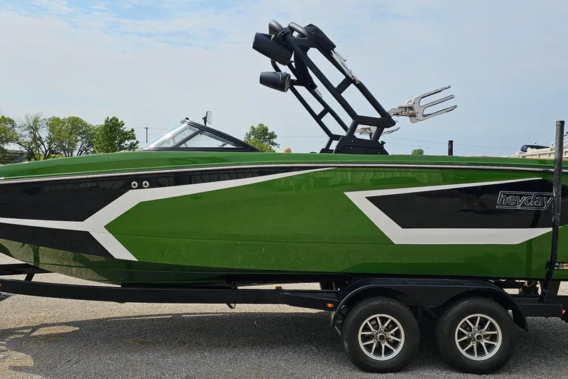 Slide: The Image of 2025 Heyday WTSurf boat in green and black on a trailer. - 1
