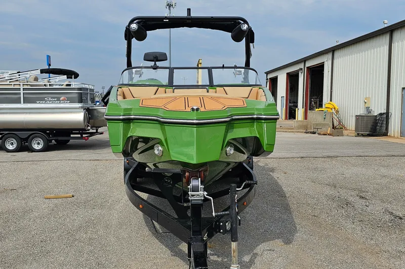 Slide: The Image of 2025 Heyday WTSurf boat in vibrant green, parked outdoors near a warehouse. - 2