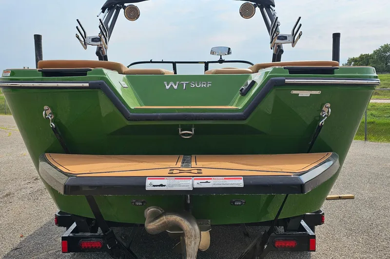 Slide: The Image of 2025 Heyday WTSurf boat, green exterior, rear view with swim platform and speakers. - 3
