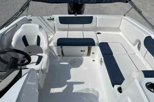 Slide: The Image of 2023 Tahoe 2150 boat interior with white and navy seating, steering wheel, and spacious layout. - 9