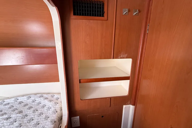 Slide: The Image of Interior of a 2010 Leopard 38 boat cabin with wooden paneling and built-in shelving. - 100