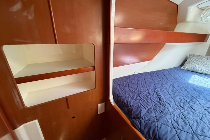 Slide: The Image of Cozy cabin interior of 2010 Leopard 38 with wooden shelves and blue bedding. - 112