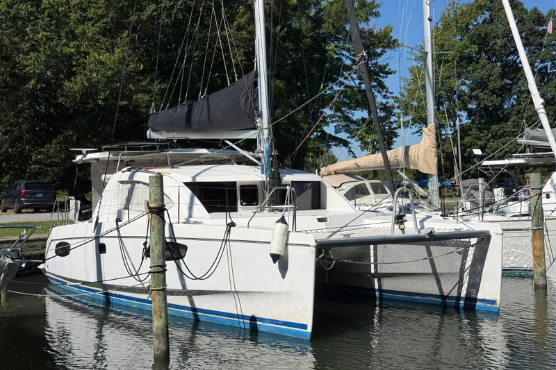 Slide: The Image of 2010 Leopard 38 catamaran docked in a marina, surrounded by trees and other boats. - 4