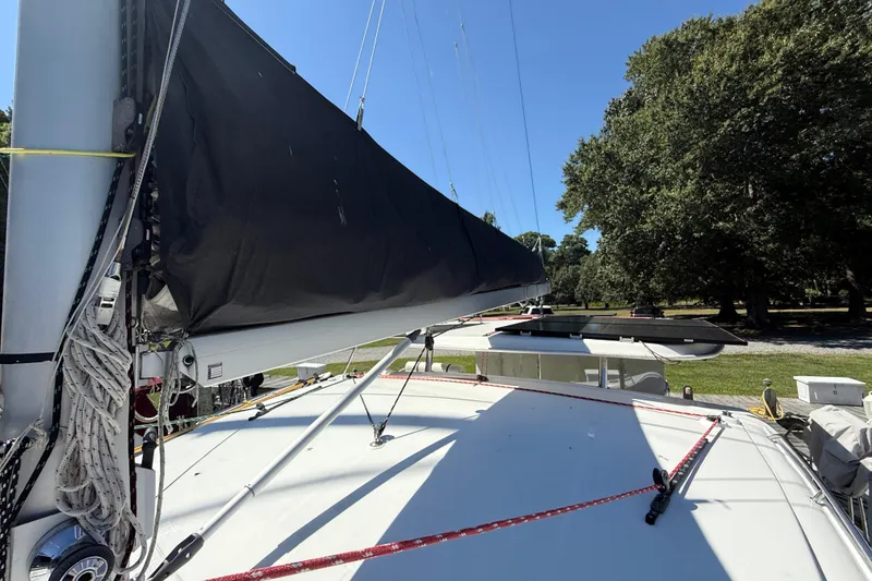 Slide: The Image of 2010 Leopard 38 sailboat with black sail cover, docked near lush greenery. - 42