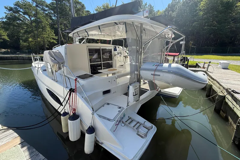 Slide: The Image of 2010 Leopard 38 catamaran docked, featuring a dinghy and spacious deck area. - 6