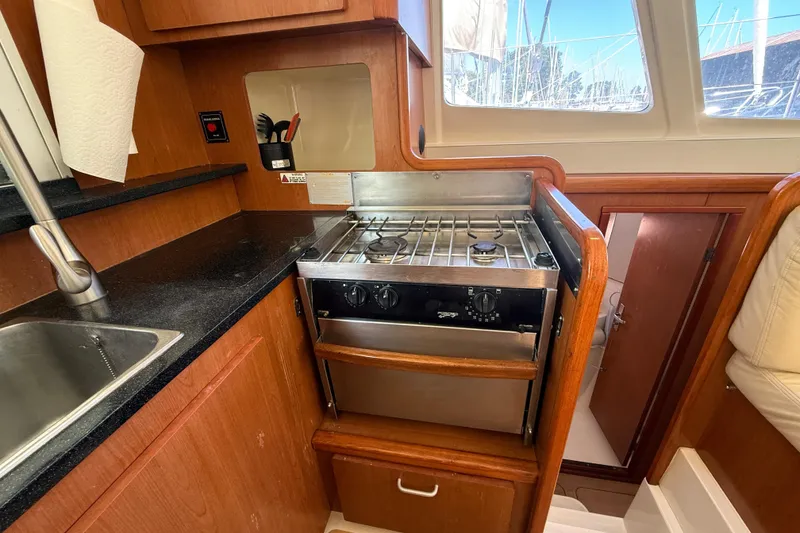 Slide: The Image of Compact kitchen in a 2010 Leopard 38 yacht with stove, sink, and wooden cabinetry. - 61