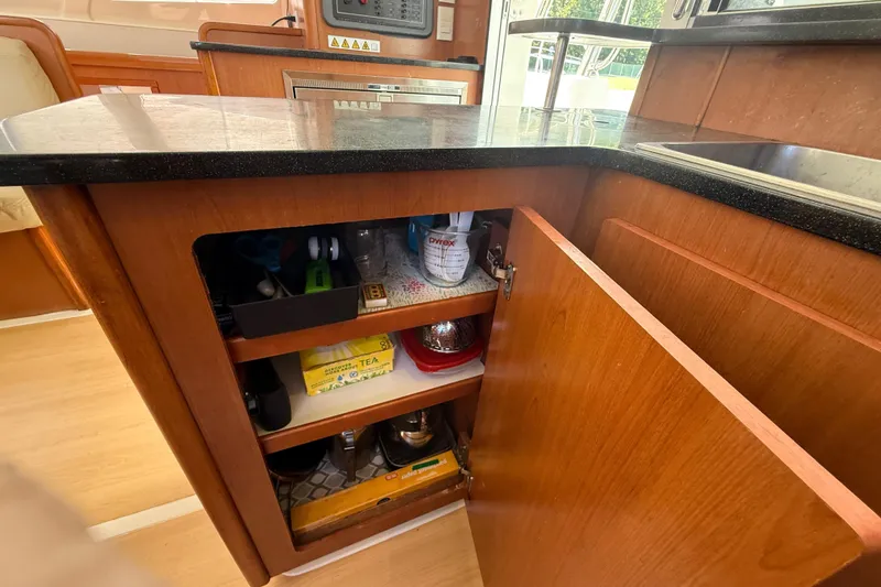Slide: The Image of Kitchen cabinet in a 2010 Leopard 38 yacht, featuring open shelves with various items. - 69