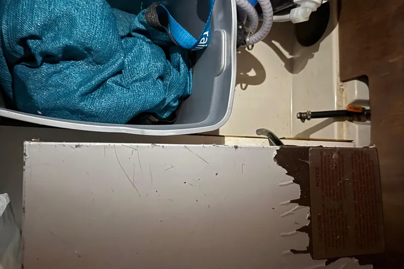 Slide: The Image of Storage compartment in a 2010 Leopard 38, containing a blue fabric and plumbing components. - 79