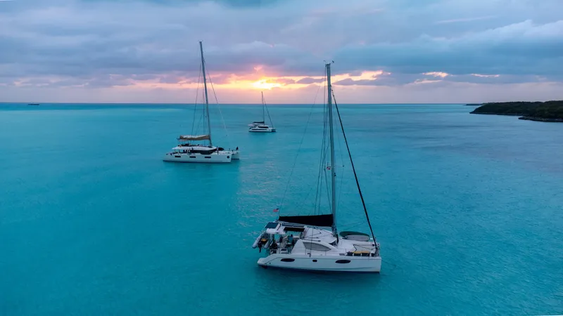 Slide: The Image of Sailboats anchored in turquoise waters at sunset, featuring a 2010 Leopard 38 catamaran. - 8