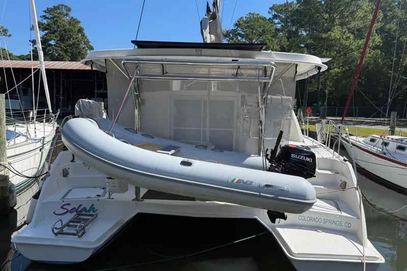 Slide: The Image of 2010 Leopard 38 catamaran with dinghy and Suzuki outboard motor, docked in a marina. - 9