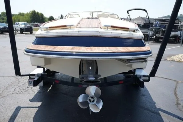 Slide: The Image of 2015 Chris-Craft Capri 21 boat on trailer, rear view, showcasing propeller and wooden deck. - 4
