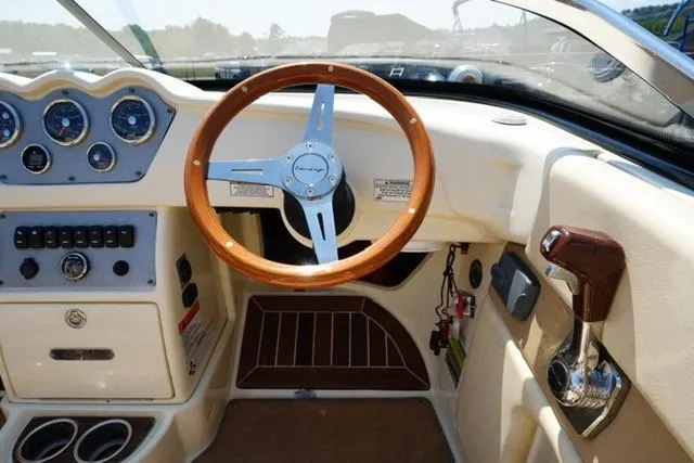 Slide: The Image of Interior of a 2015 Chris-Craft Capri 21 boat, featuring a classic wooden steering wheel. - 9