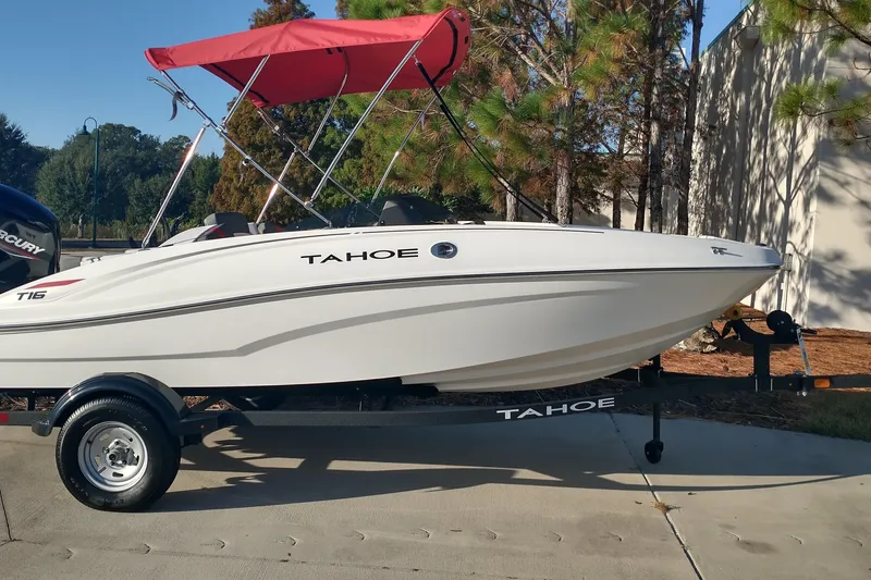 Slide: The Image of 2026 Tahoe T16 boat with red canopy on trailer, parked outdoors. - 1