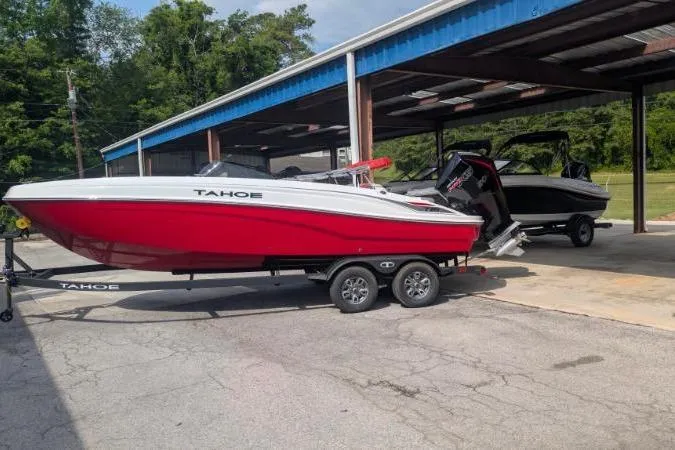 The Image of 2026 Tahoe T21 boat in red and white on a trailer, parked outdoors. - 0
