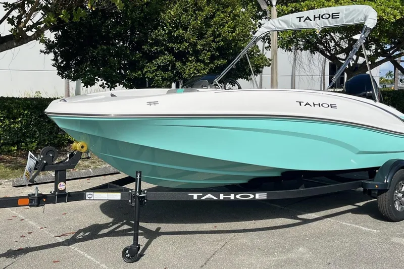 Slide: The Image of 2026 Tahoe T16 boat on trailer, turquoise and white design, parked outdoors. - 2